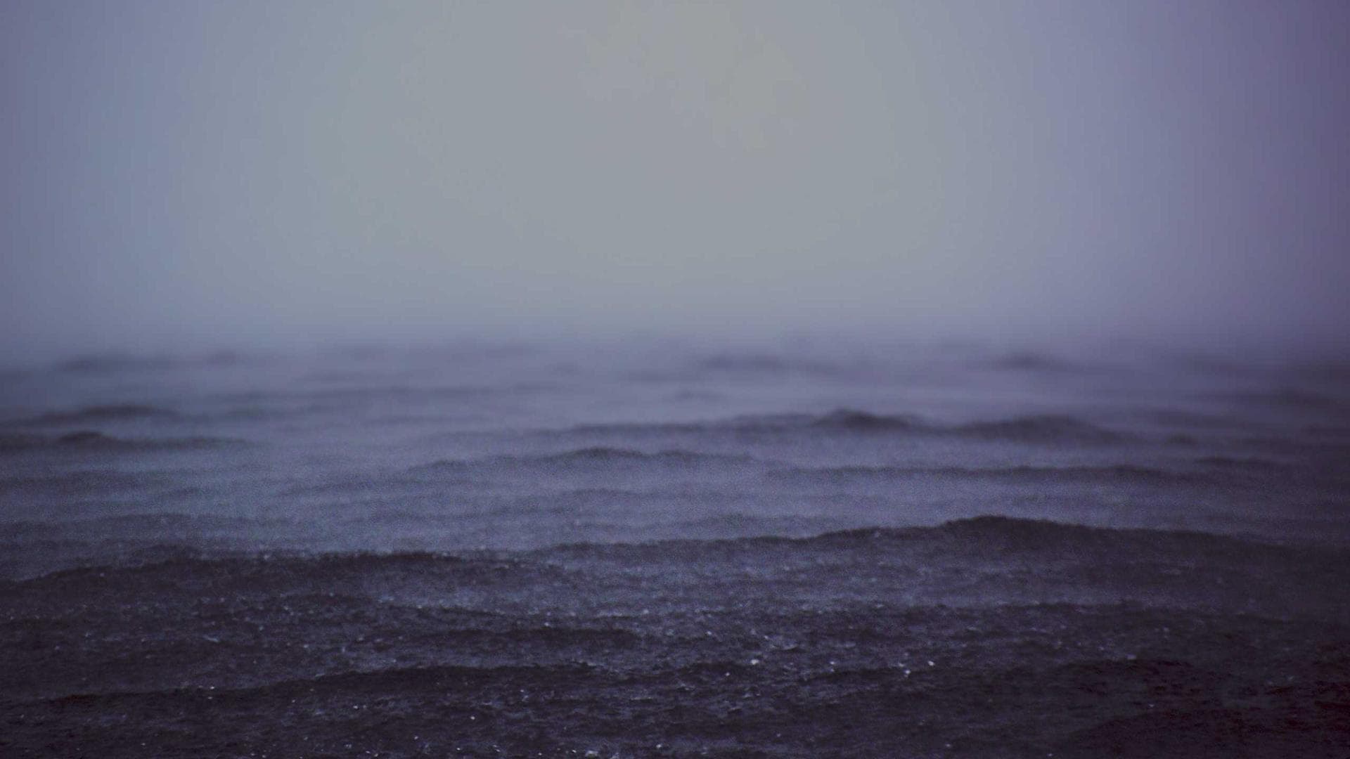 A band performing on stage in a dark venue with dramatic, fire-colored lighting.